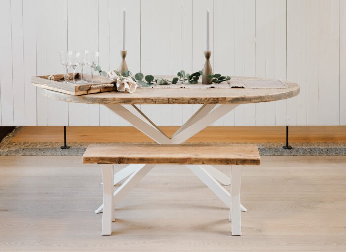 Ovaler Esstisch aus altem Bauholz mit markanten Beinen in sternform.